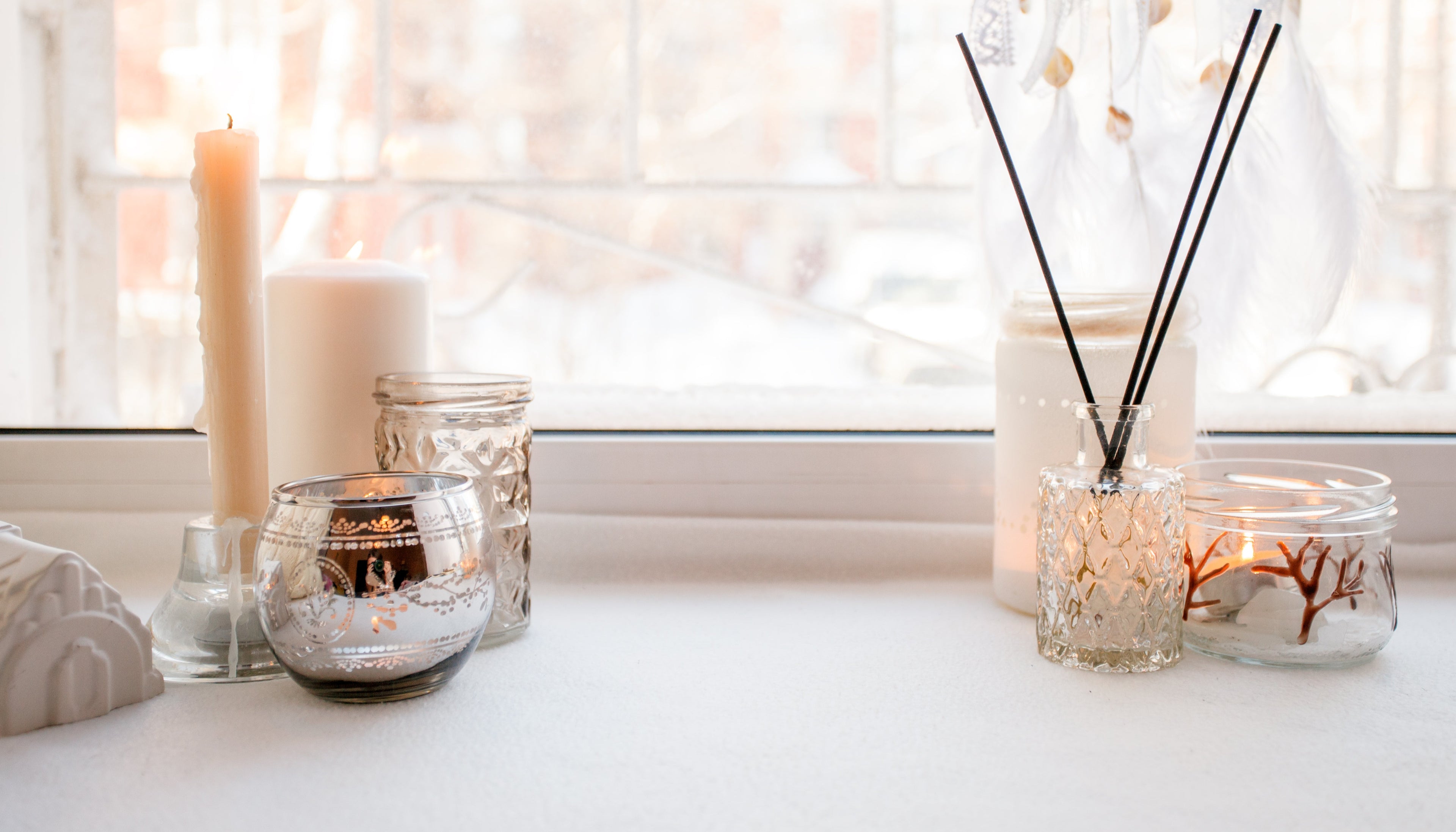 Decorative items including candles and diffusers on a windowsill with soft lighting.